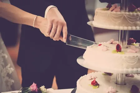 Wedding photo: bride cutting tiered cake closeup