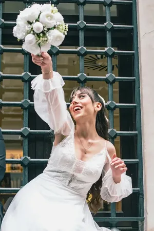 Wedding photo: bride raising bouquet celebrating gate