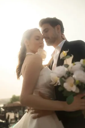 Wedding photo: couple embracing sunset white bouquet