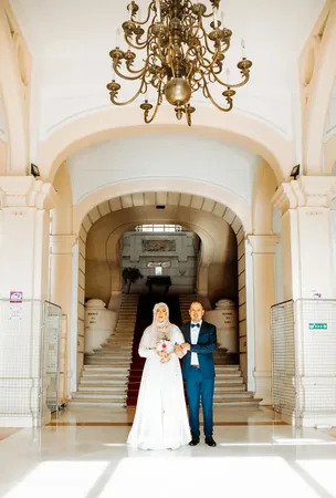 Wedding photo: couple grand hall chandelier hijab