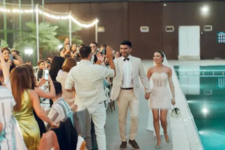Wedding photo: couple high five entrance poolside