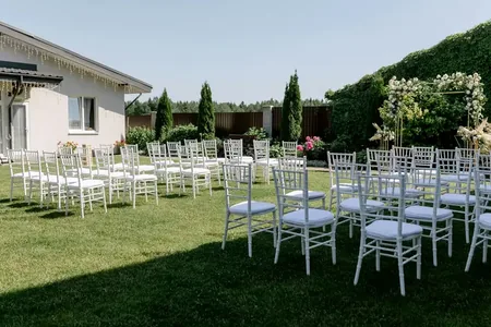 Wedding photo: outdoor ceremony white chairs garden